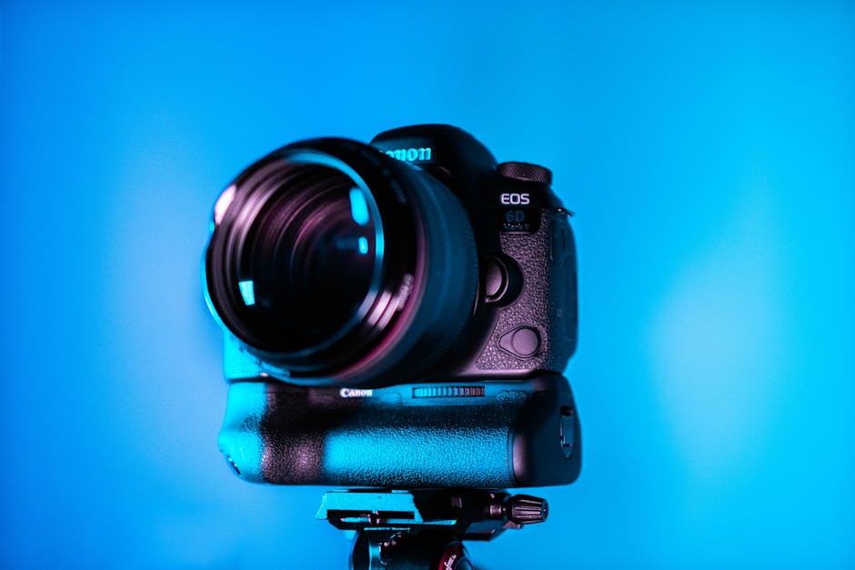Close-up of a Canon DSLR camera with lens in vibrant blue studio lighting. Professional photography equipment.