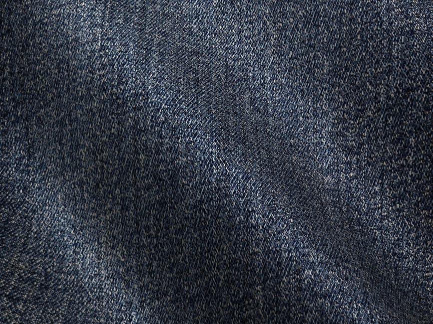 Detailed texture of blue denim fabric with visible grain and folds.