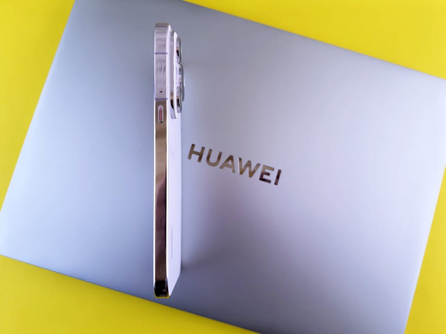 Side view of a smartphone placed on a laptop featuring the Huawei logo on a vibrant yellow background.