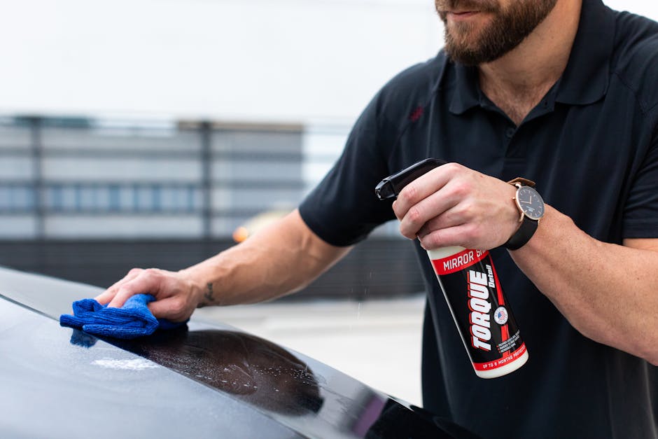 Man cleaning car with spray and cloth for shiny finish. Perfect for auto maintenance themes.