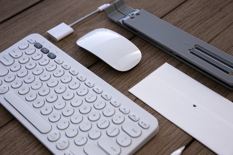 A sleek workspace setup featuring a wireless keyboard, mouse, and adapter on a wooden desk.