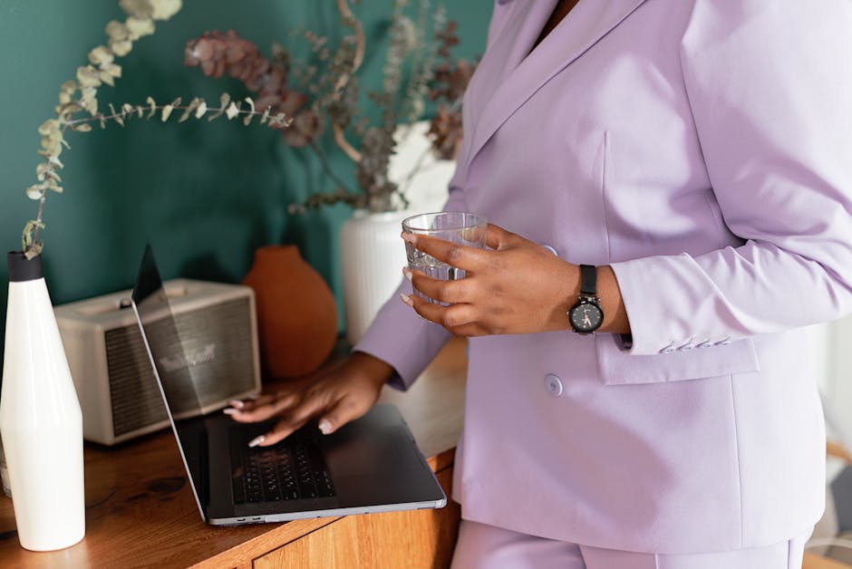 Professional woman in lilac suit working on a laptop in an office setting.