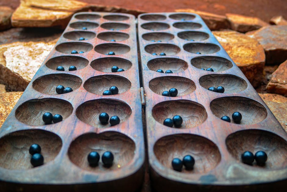 Close-up of a wooden Mancala board with stones outdoors in Uganda.