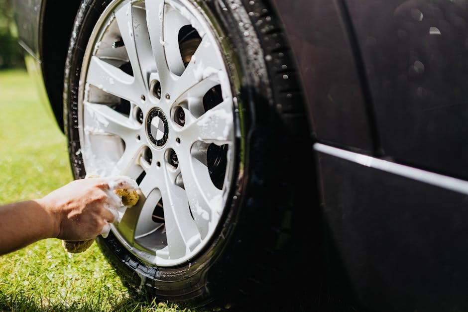 Detailed shot of a car wheel being cleaned at home in a sunny outdoor setting.