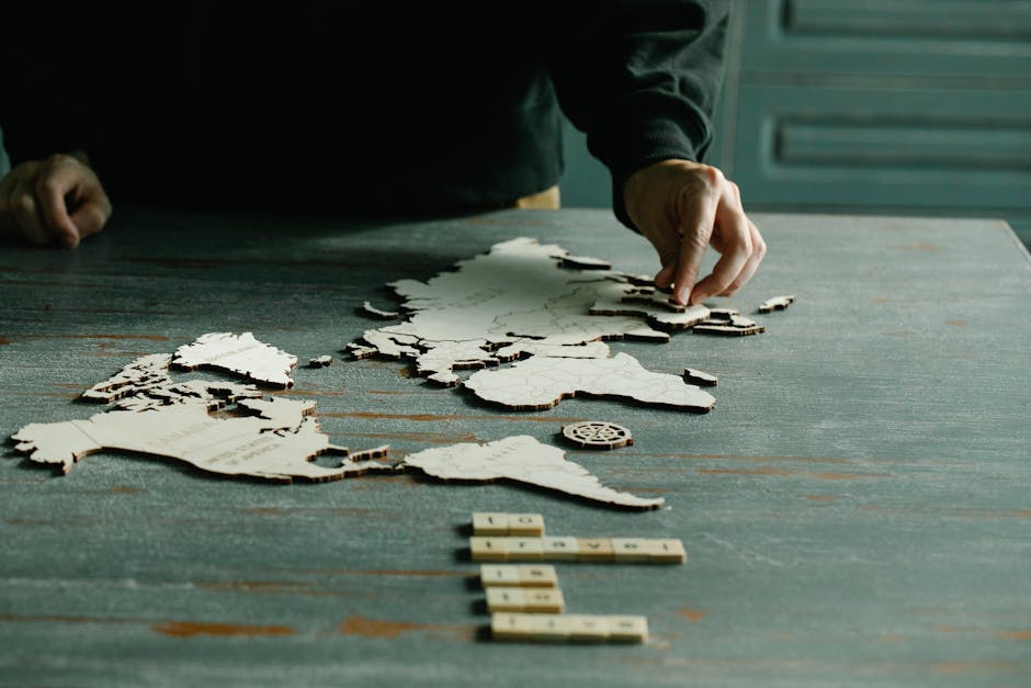 A person arranging a wooden puzzle of a world map on a rustic wooden table.