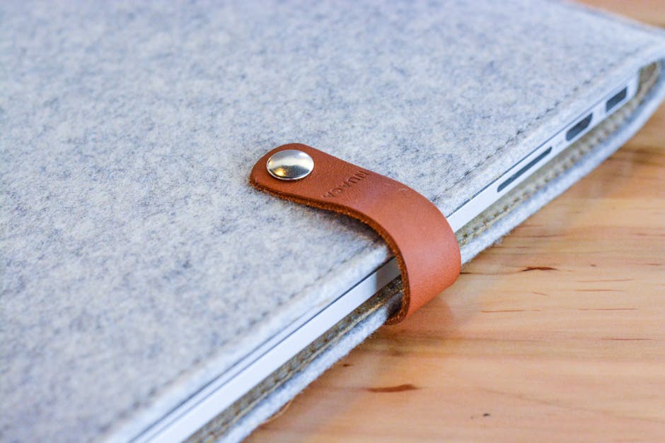 A stylish felt and leather laptop sleeve sits elegantly on a wooden table, offering sleek protection.